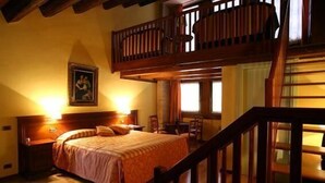 Quarto com cama de madeira, mesa de cabeceira, pintura na parede e varanda com guarda-corpo de madeira.
