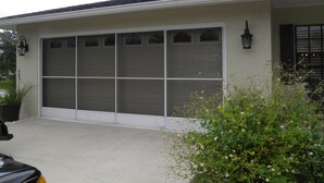 A single-story building with a large garage door, a potted plant, and a small bush in the foreground. - Salt Water Canal home w/Dock, Family/Pet Friendly, close to Beach and A1A (Palm Coast)