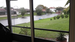 A view through a window with a grassy area, a body of water, and houses in the background. - Salt Water Canal home w/Dock, Family/Pet Friendly, close to Beach and A1A (Palm Coast)