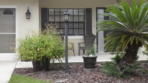 A house with a porch, potted plants, a chair, and a street lamp. - Salt Water Canal home w/Dock, Family/Pet Friendly, close to Beach and A1A (Palm Coast)