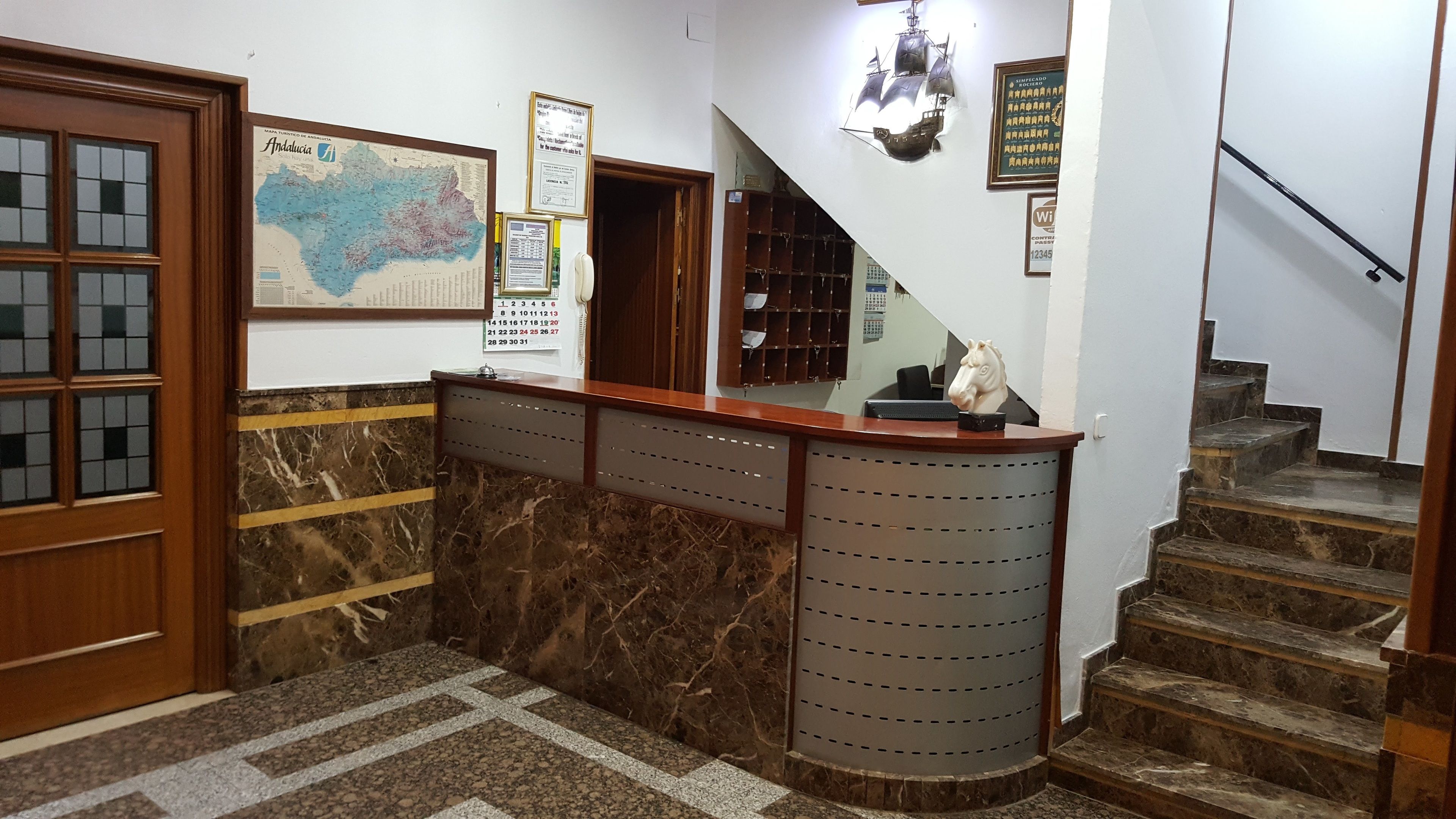 Un área de recepción con mostrador de mármol, un mapa en la pared y una escalera.