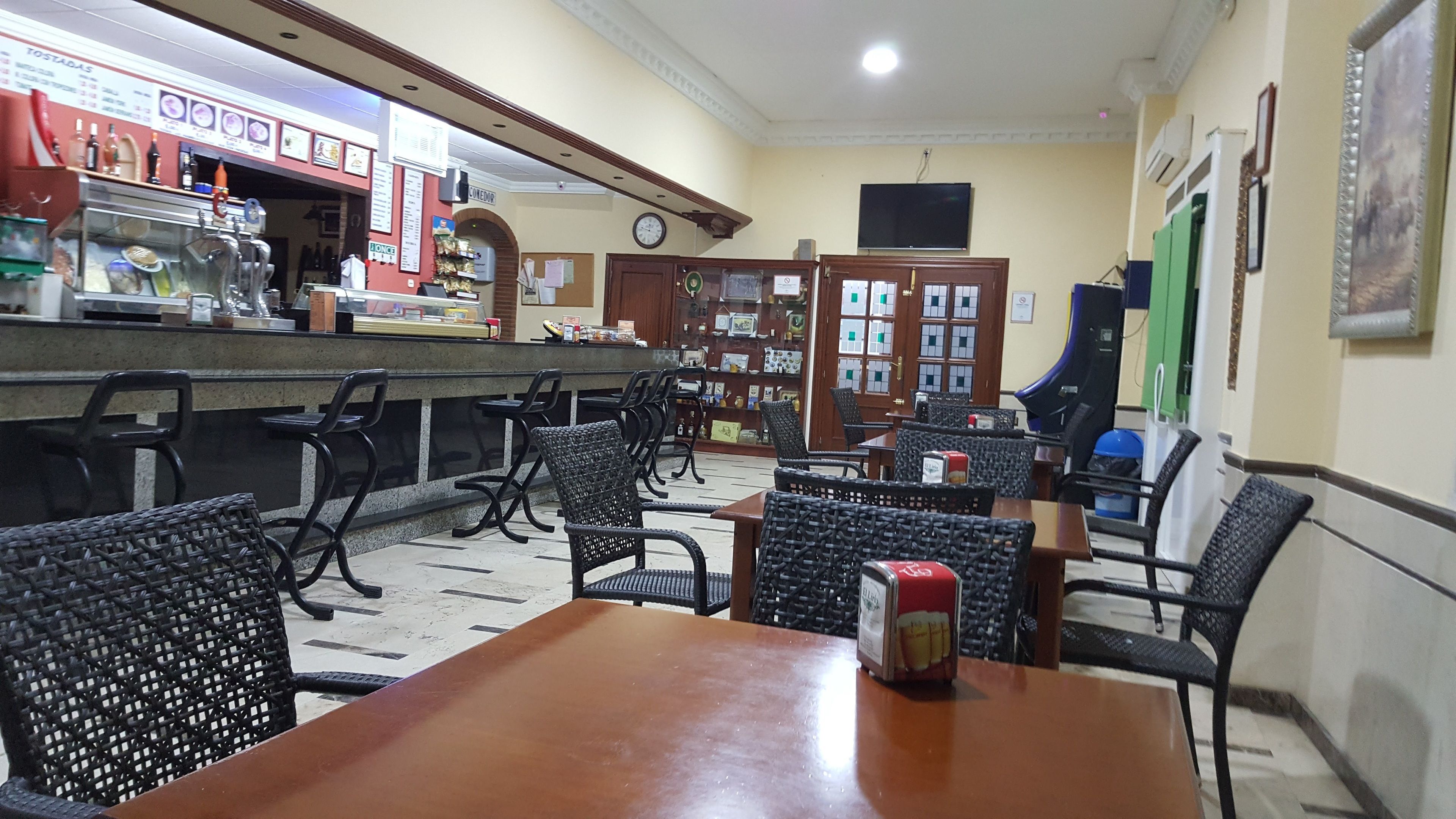 Ein Restaurantinneres mit Barbereich, mehreren Tischen und Stühlen sowie einer Auswahl an Speisen und Getränken.