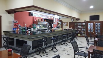 Zona de bar con mostrador, taburetes y cartel de menú.