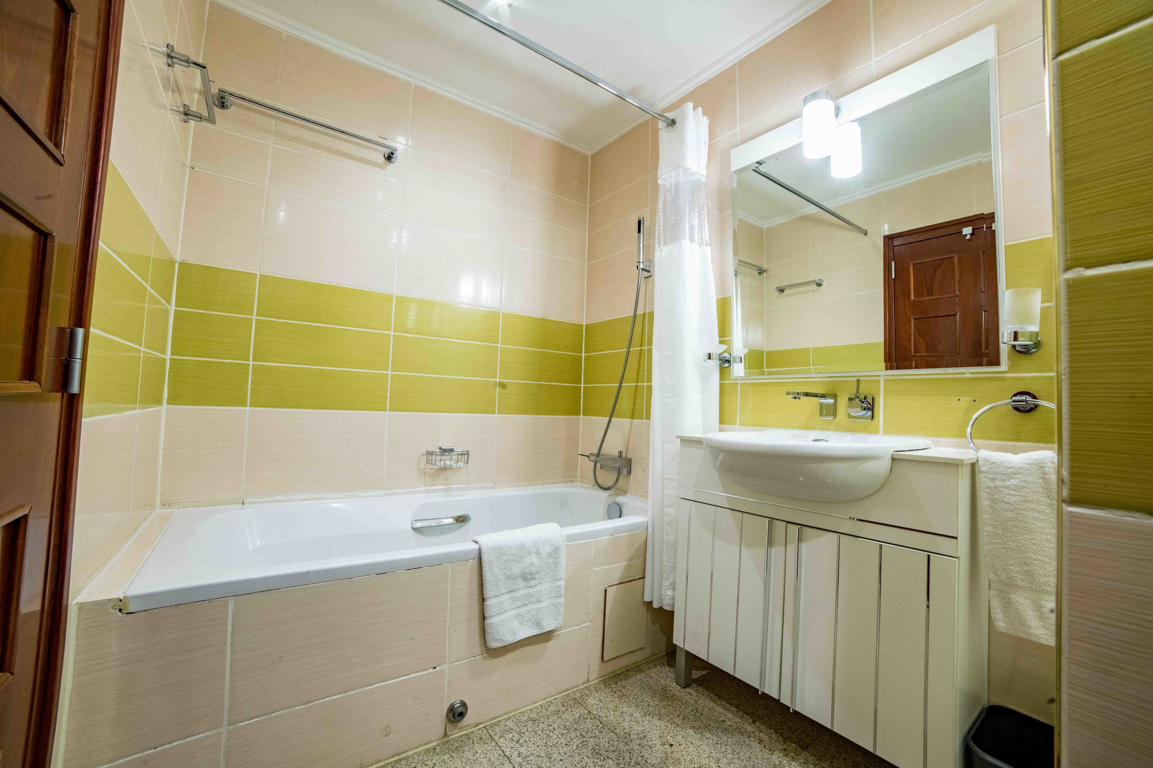 A bathroom with a bathtub, a sink, and a mirror.