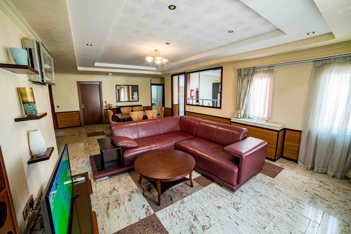 Zona d'estar àmplia amb un sofà de cuir, una taula de centre i un televisor de pantalla plana.