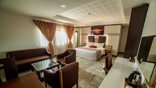 Quarto de hotel com cama, sofá, mesa de centro e escrivaninha.