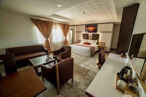 Une chambre d’hôtel avec un lit, un canapé, une table basse et un bureau.