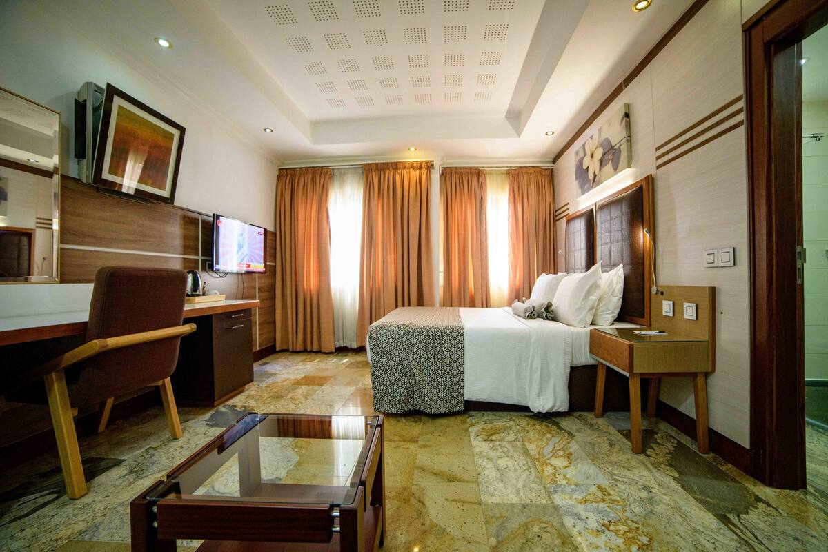 Habitació d'hotel amb llit, escriptori, cadira i televisió.