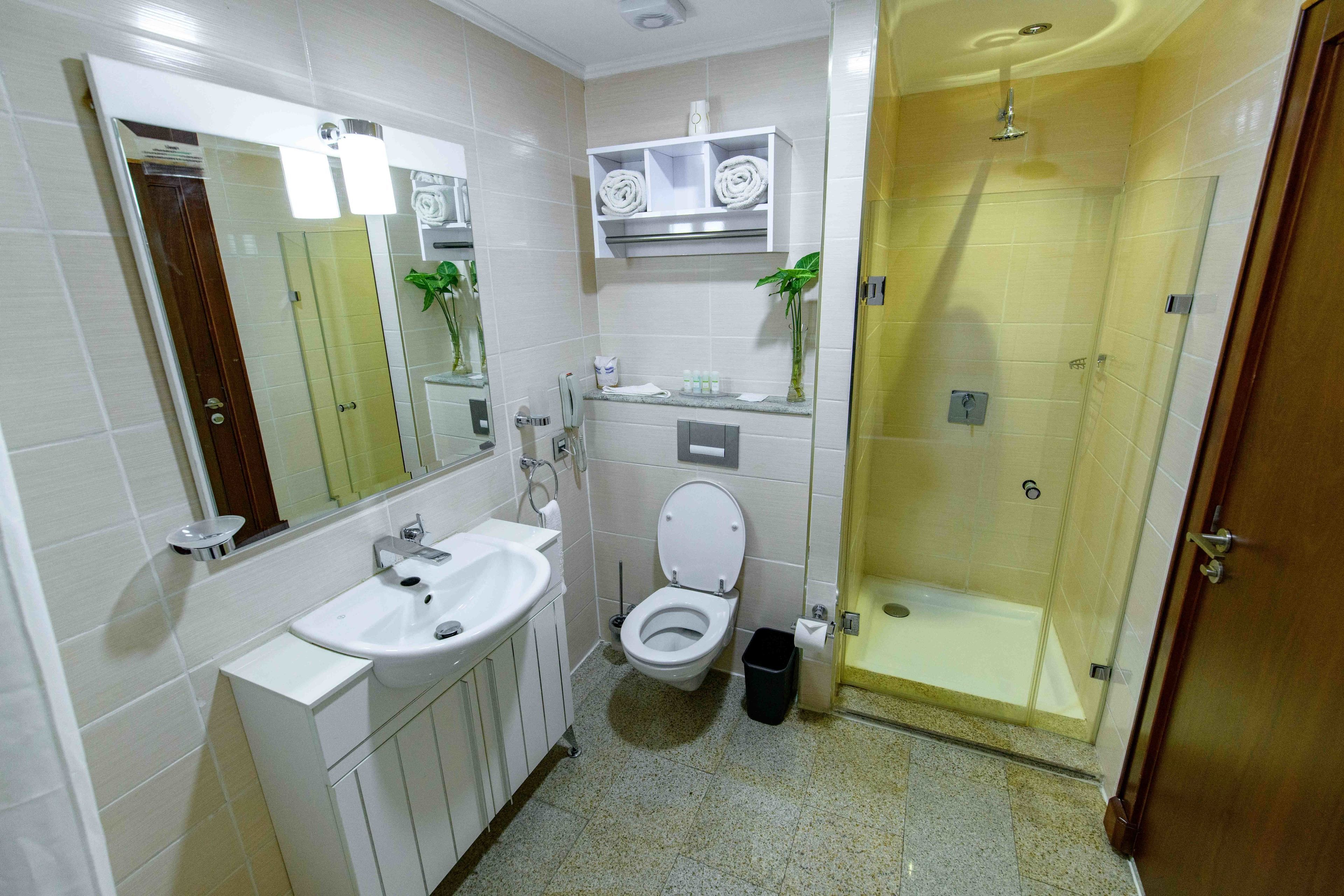 Un baño moderno con lavabo, inodoro y ducha con mampara de vidrio.