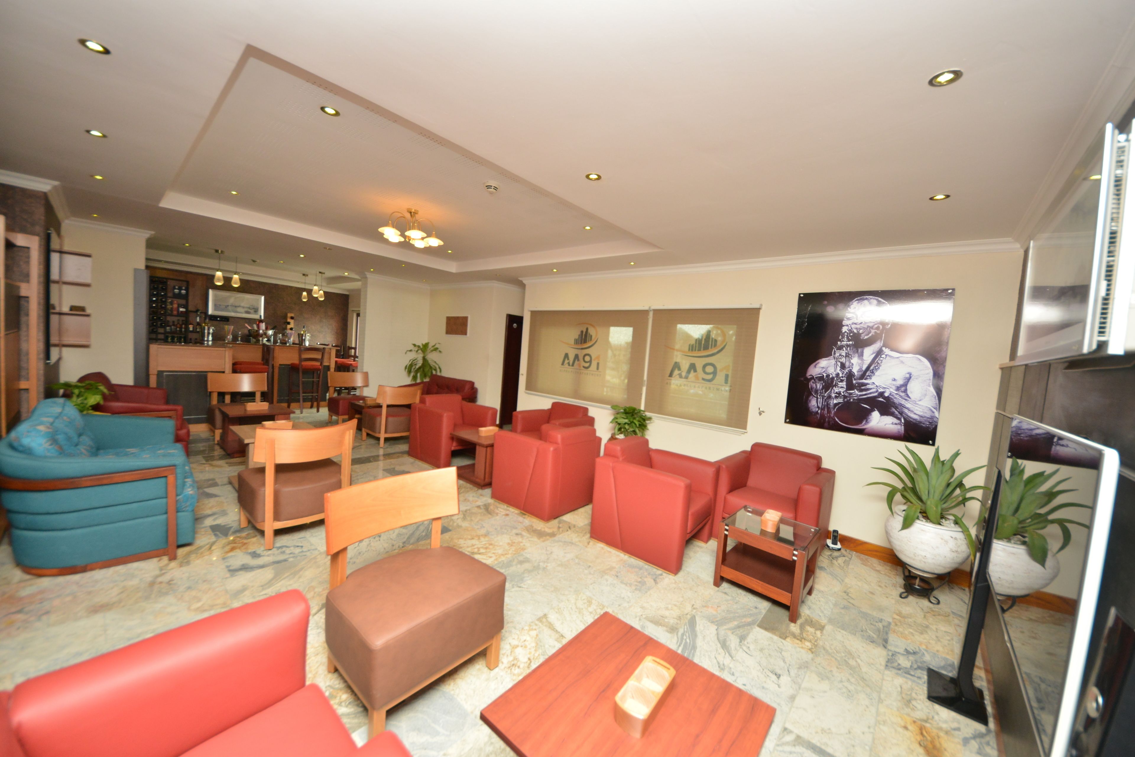 A spacious lobby with red and blue seating, a bar area, and a television.