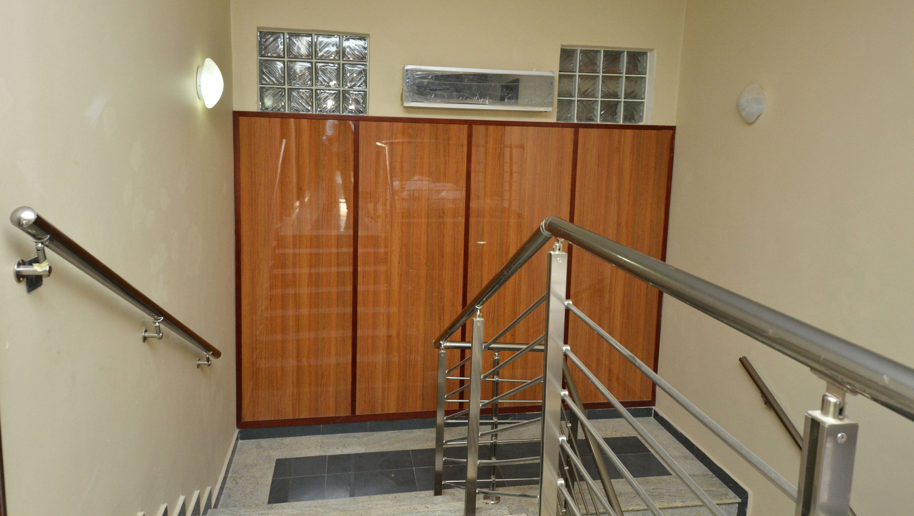 A staircase with metal railings, wooden doors, and a tiled floor.