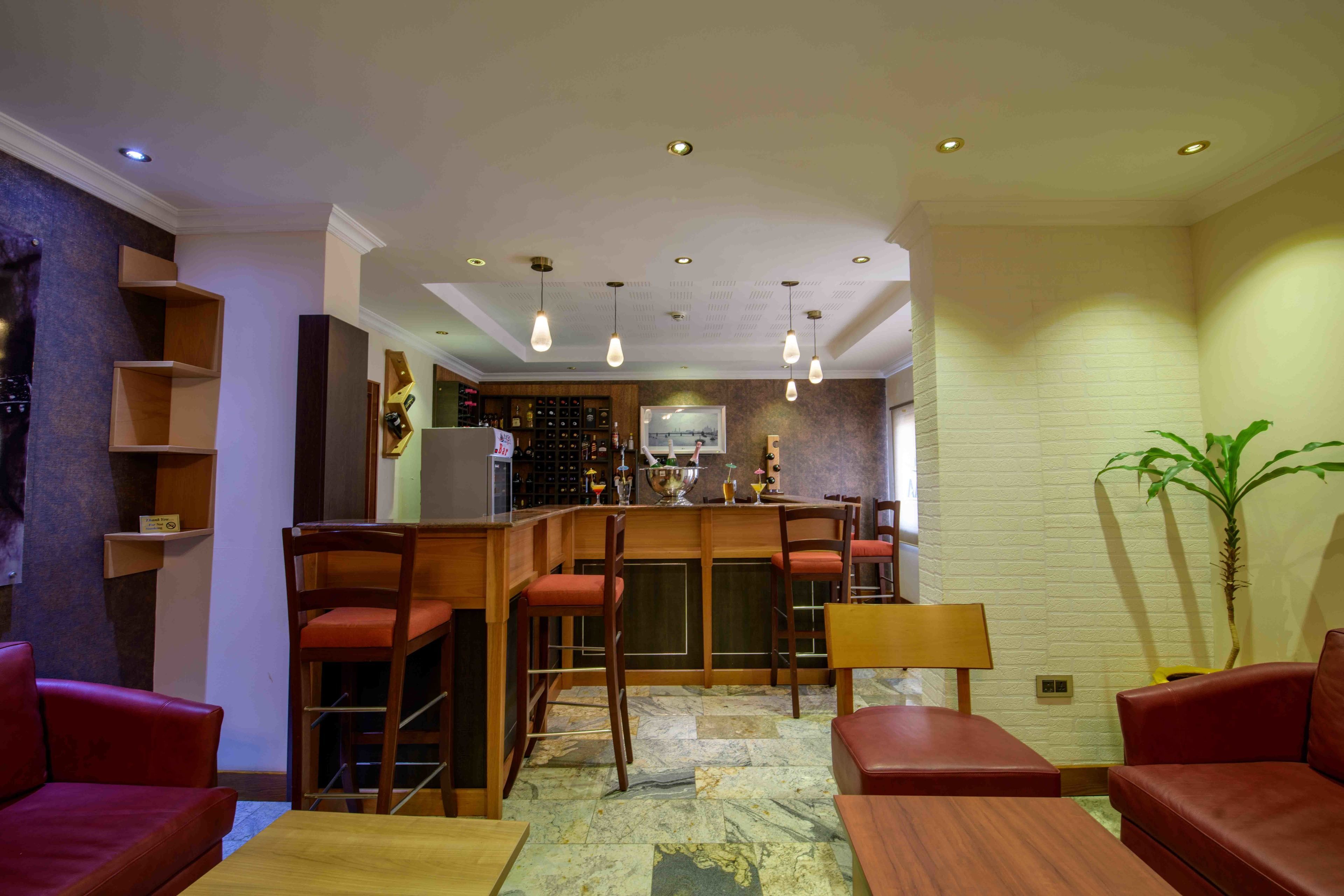 Una cocina moderna con barra, muebles de madera y suelo de mármol.