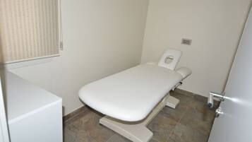 An examination room with a white examination table and tiled floor.