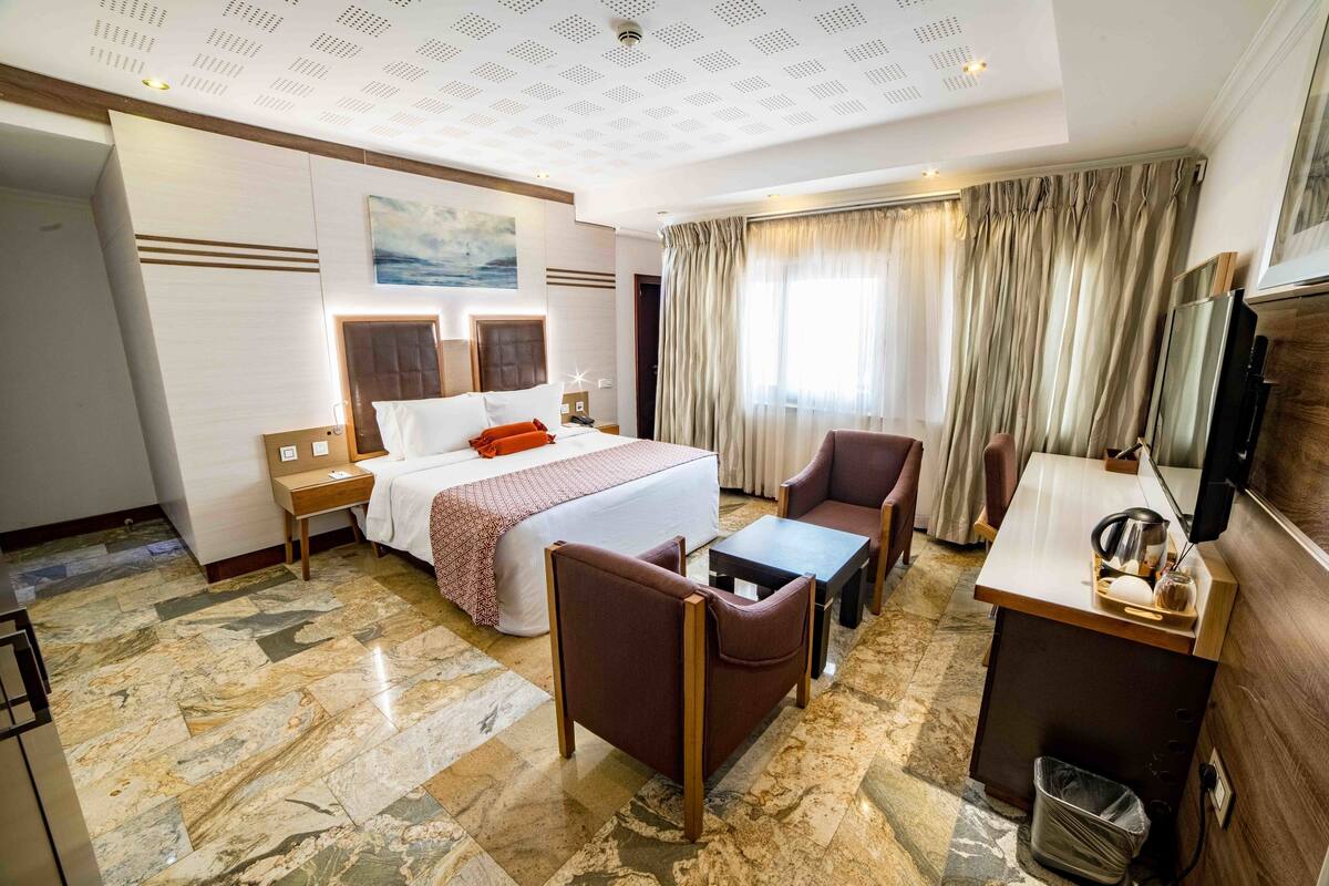 Una habitació d'hotel amb llit, escriptori, cadira, taula petita i televisió.