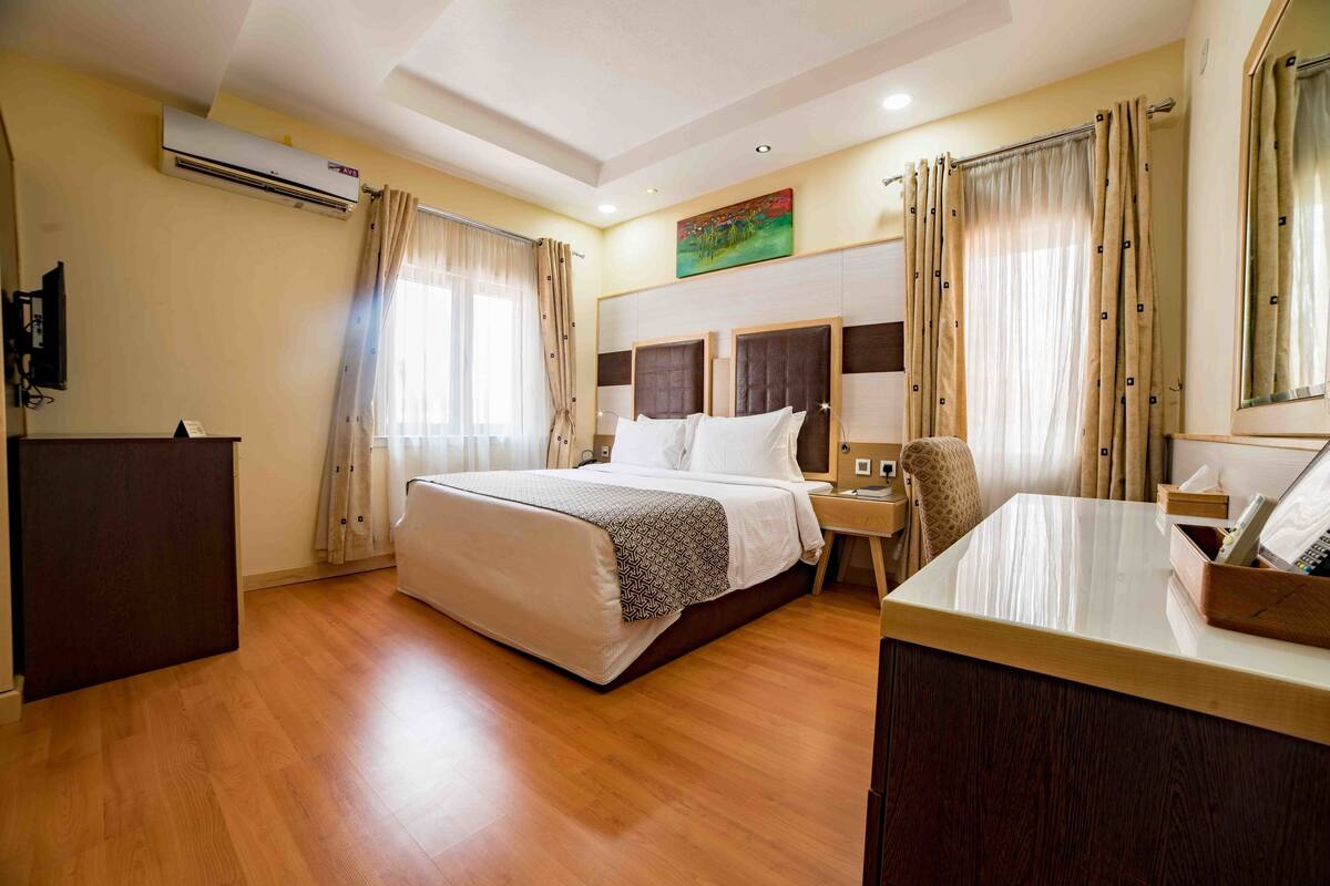 Una habitació d'hotel amb un llit gran, una taula de treball amb un telèfon i un aparell d'aire condicionat a la paret.