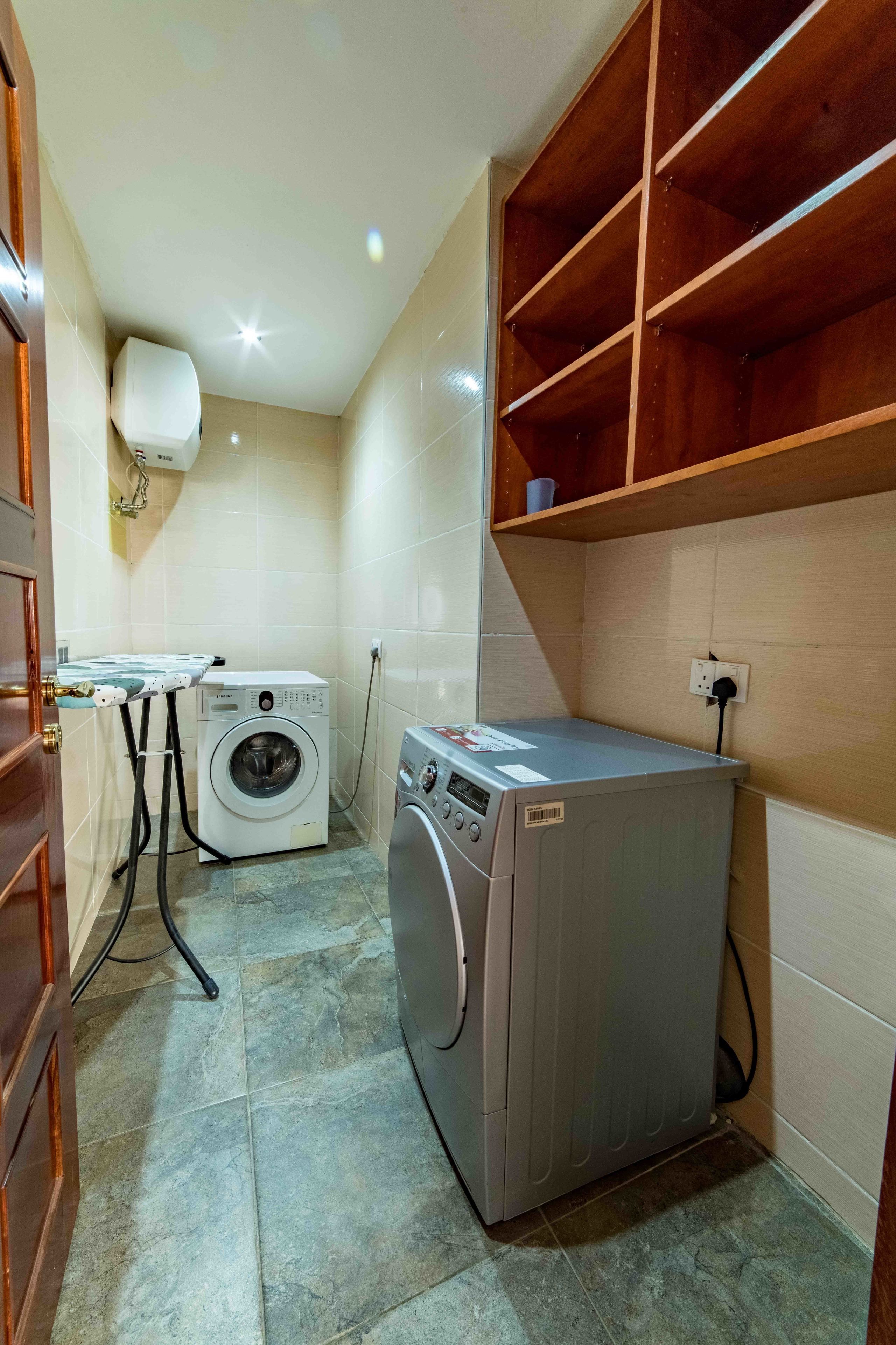 A compact laundry area with a washing machine, a dryer, and a small ironing station.
