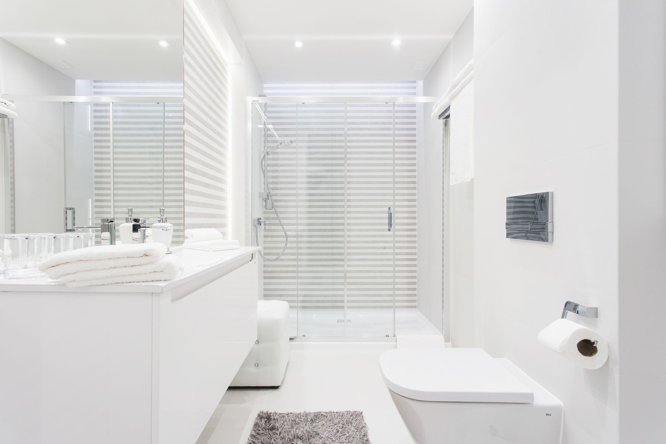A modern bathroom with a glass shower enclosure, a white toilet, and a vanity with a mirror.