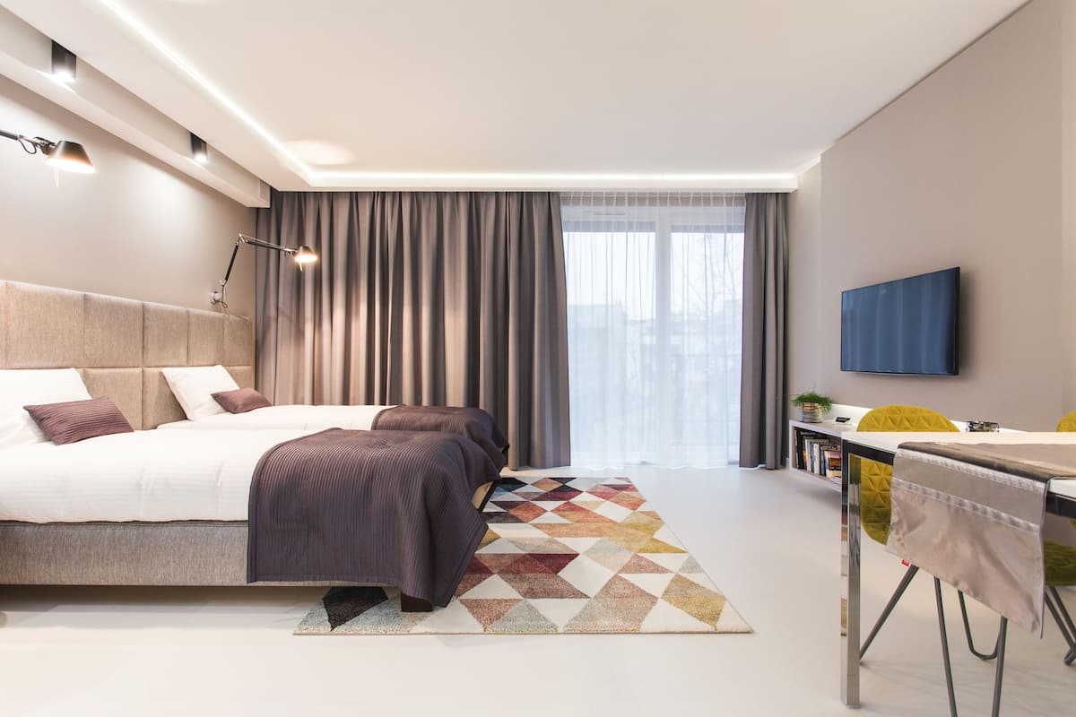A modern bedroom with a large bed, a desk, and a television.