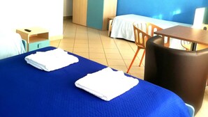 Una camera d'albergo con un letto, una scrivania, una sedia, un armadio e una televisione.