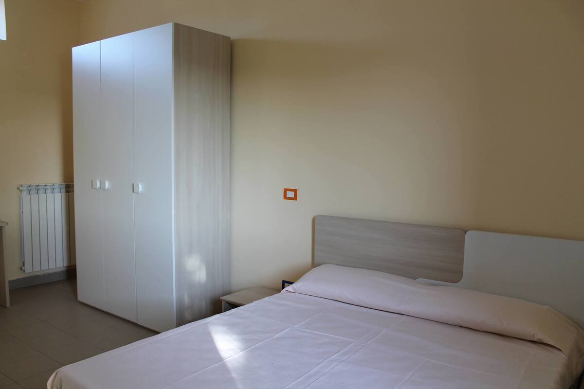 A bedroom with a bed, a wardrobe, and a nightstand.