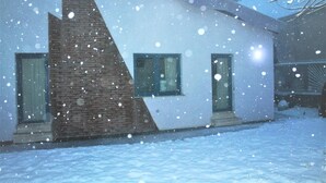 Un edificio moderno con una sezione in mattoni e pareti bianche, immerso nella neve.