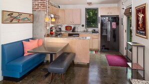 A compact kitchen with a built-in fridge, a dining area with a bench, and a blue sofa. - Folly Vacation 204 Getaway, Relax & Unwind (Folly Beach)