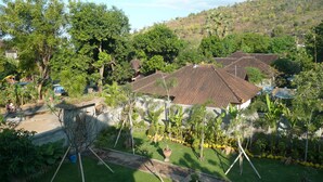A residential area with houses, lush greenery, and a hilly landscape in the background. - Villa Zukunft Babonsay (Karangasem)