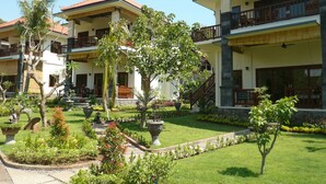 A hotel with multiple-story buildings, balconies, and a well-maintained garden with various plants and a pathway. - Villa Zukunft Babonsay (Karangasem)