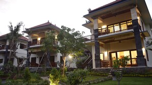 A two-story building with a balcony, surrounded by a well-maintained garden with various plants and trees. - Villa Zukunft Babonsay (Karangasem)