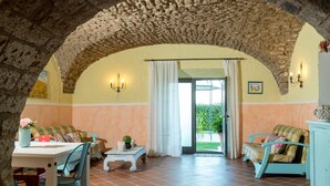 A cozy room with a stone archway, a dining table with chairs, a sofa, and a cabinet. - Il Raggio di Sole (Bagnoregio)