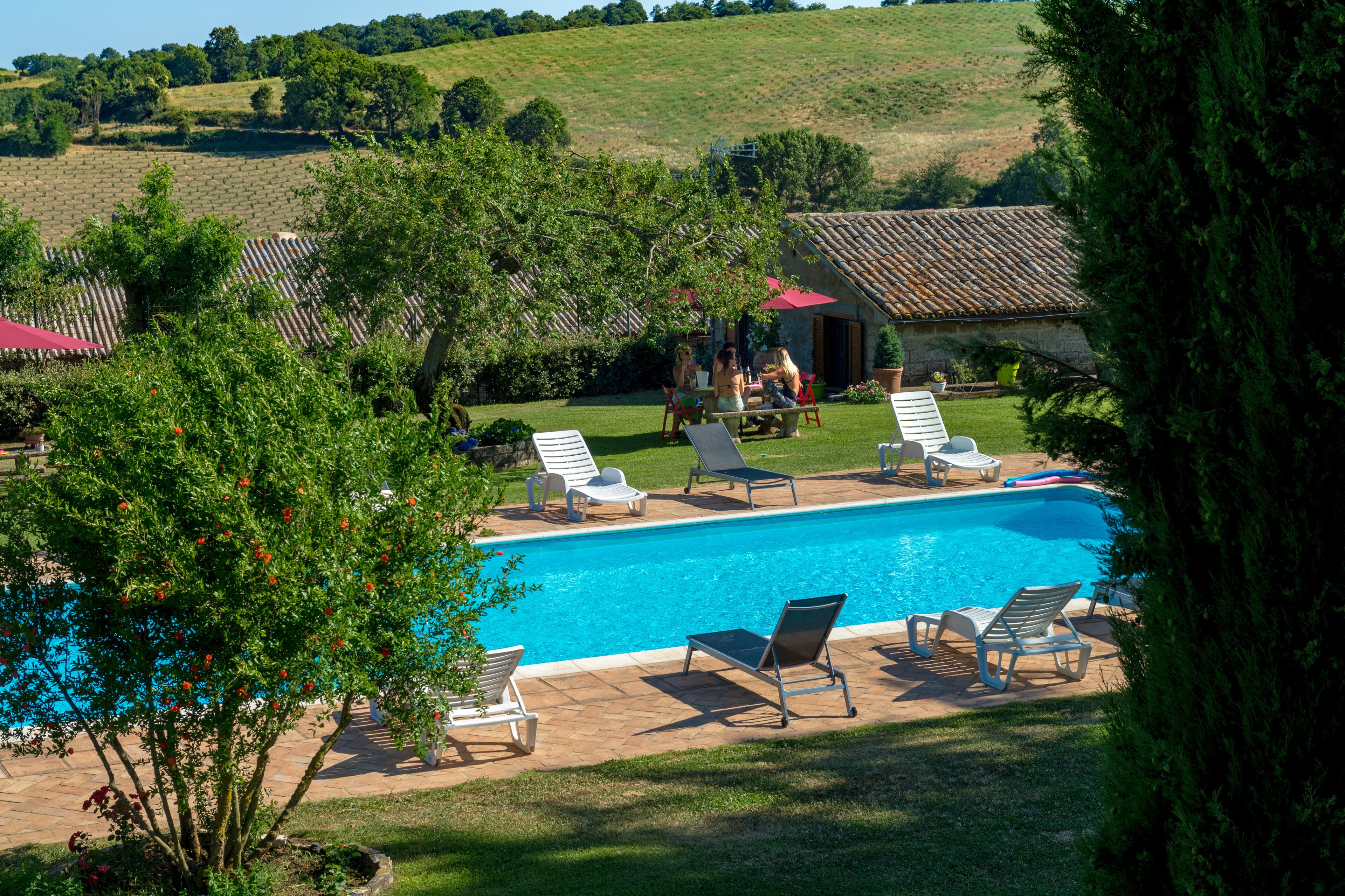 A swimming pool with lounge chairs and a small building in the background.
