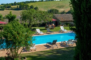 A swimming pool with lounge chairs and a small building in the background.
