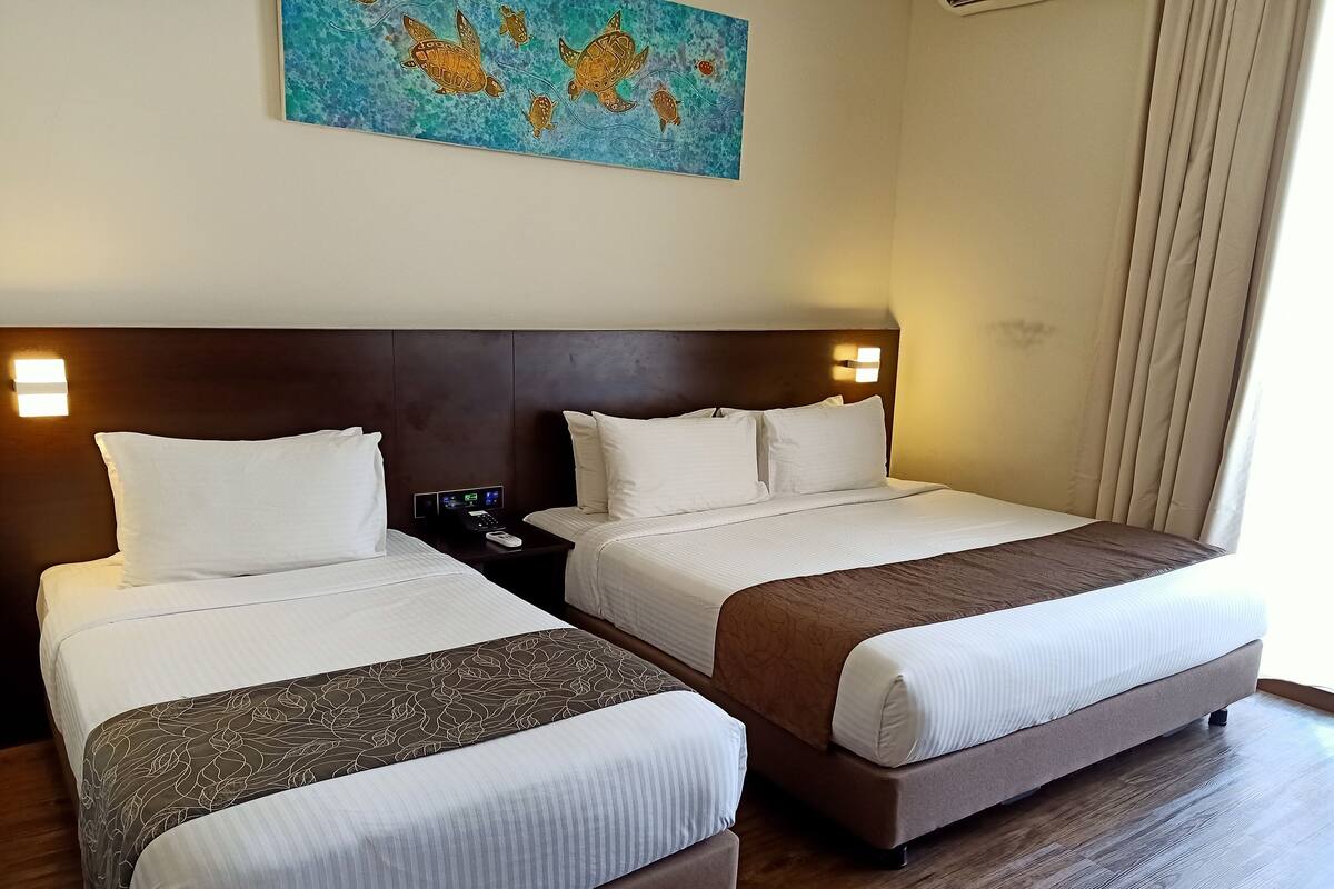 A hotel room with two beds, a nightstand with a phone and a digital clock, a painting on the wall, and a window with curtains.