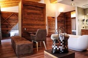 A modern interior with a wooden accent wall, a white bathtub, and a seating area with a checkered bag.