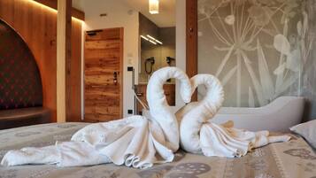 Una camera d'albergo con un letto, una porta in legno, uno spazio doccia e una parete con motivo floreale.