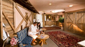Ein Zimmer mit Holzboden, einem Empfangstresen, einem Sofa, einem Tisch und einem gemusterten Teppich.