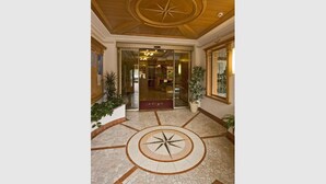 Eine Lobby mit einem zentralen, kreisförmigen Boden, einer Holzboden-Decke mit Sternenmuster und Glastüren zu einem Raum.