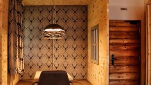 Ein gemütliches Zimmer mit Holzbalkendecke, einer Wand mit Muster und einem kleinen Tisch mit Stuhl, sowie einer dekorativen Handtuch-Anordnung in Form eines Schwans.