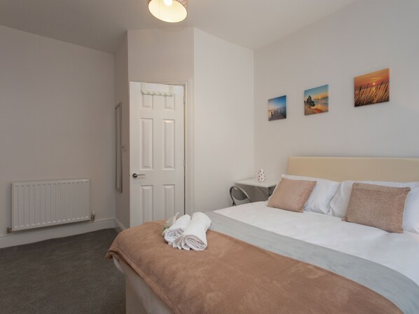 Une chambre d’hôtel avec un lit, un radiateur, une porte et trois tableaux accrochés au mur.
