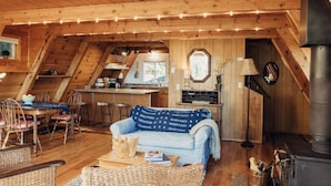 A cozy wooden interior with a dining area, a sofa, and a kitchen.