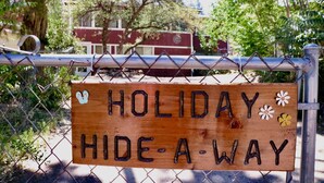 A wooden sign with the text "HOLIDAY HIDE-A-WAY" attached to a chain-link fence. -  Holiday Hide Away  (Payson)