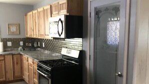 A kitchen with wooden cabinets, a black stove, and a refrigerator. -  Holiday Hide Away  (Payson)