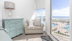 A room with a beige sofa, a teal dresser, and a view of a pool and beach. - 2000sqft Beachfront Beauty on Perdido Key.  (Pensacola)