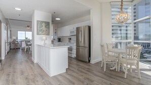 A spacious kitchen with a large island, stainless steel appliances, and a dining area with white chairs. - 2000sqft Beachfront Beauty on Perdido Key.  (Pensacola)