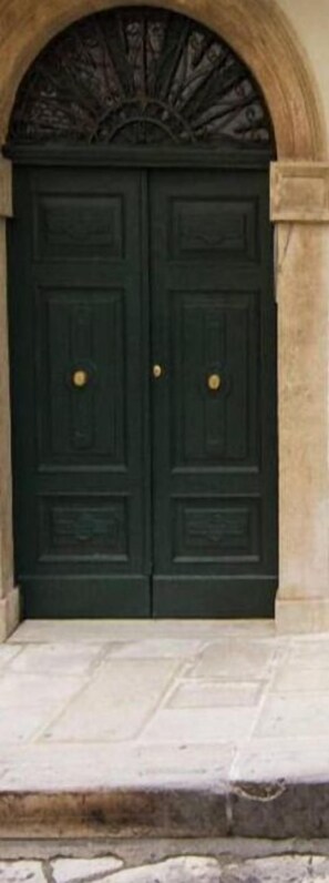 A dark green double door with a decorative arch above it. - B&B Fighera (Gravina in Puglia)