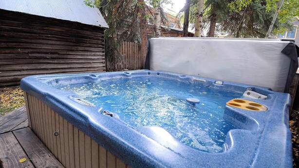 Een hottub in een buitengebied met een houten terras en een houten omheining op de achtergrond.