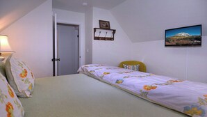 Een slaapkamer met een bed, een stoel, een deur, een aan de muur hangend schilderij en een lamp.