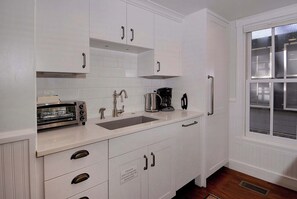 A kitchen with white cabinets, a toaster, a coffee maker, and a window with blinds. - Historic Elk Ave Haven, Hot tub, Town of CB. (Crested Butte)