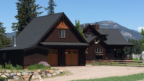 A large wooden house with a prominent front porch and a garage. - Stage Road Estate private studio apartment. (Columbia Falls)
