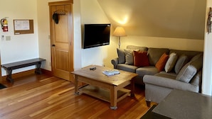 A cozy living room with a wooden coffee table, a sofa, a television, and a lamp. - Stage Road Estate private studio apartment. (Columbia Falls)